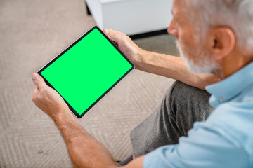 Handsome senior old man using digital tablet with mock up blank screen while sitting relaxing...