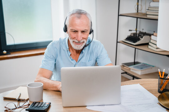Happy senior Caucasian man in wearing headphones, helping as call center consult assistant. Smiling mature 60s years old businessman holding video call with clients partners. Copy space - Powered by Adobe