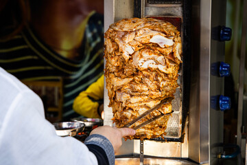 Street vendor slicing doner kebab meat. Popular fast food, rich in flavor but often high in fat and sodium, raising health concerns with frequent consumption.