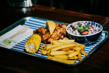 A tray of food with a bowl of coleslaw and a lemon wedge