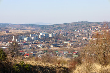 A panoramic view of a small town located in a valley among hills and forests. From a high vantage...