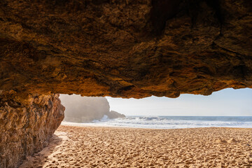 View of shoreline with caves and surfing waves near Nazare city, Portugal