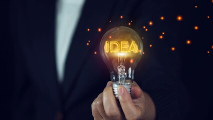Businessman holding glowing idea inside lightbulb for creative thinking idea and investment...