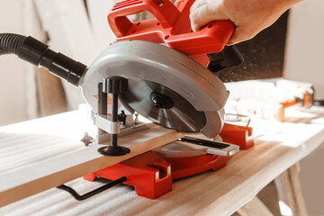 Circular saw in action as a carpenter skillfully cuts wooden planks. Hands hold the wood against the saw, showcasing precision and craftsmanship in woodworking