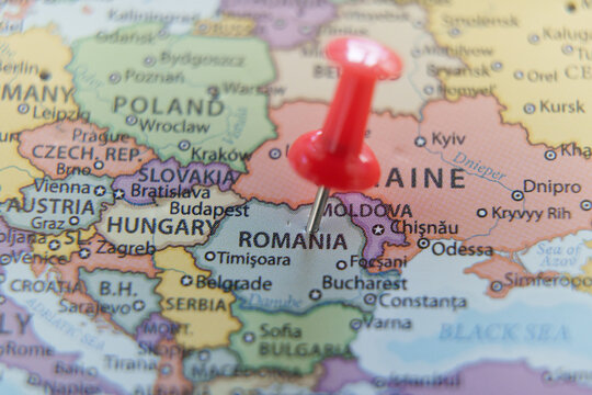 Close-up of a map with a red pushpin marking Romania. Travel, geography, and politics concept.