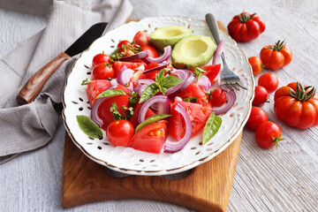 Fresh healthy avocado and tomato salad with onions on white background .
