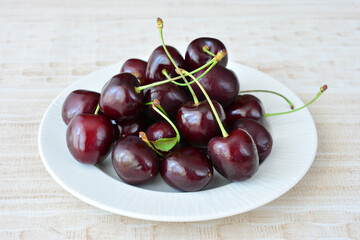 A pile of fresh juicy cherries on a white plate