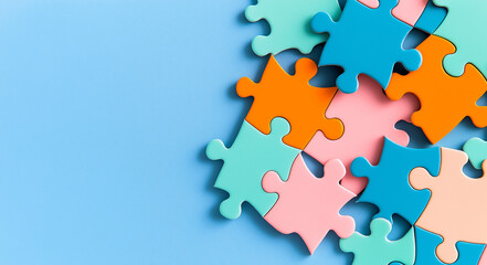 Obraz premium Colorful puzzle pieces scattered on light blue background create playful and vibrant atmosphere, inviting creativity and problem solving