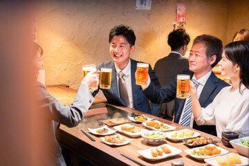居酒屋で部署のお疲れ様会をするビジネスパーソン
