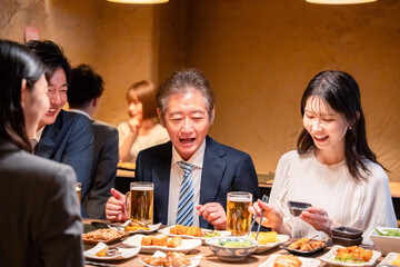 居酒屋で部署のお疲れ様会をするビジネスパーソン