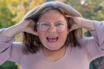 Close-up middle-aged woman with shocked and astonished expression, wide eyes and open mouth reveal...