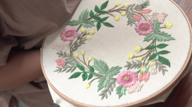 Beautiful embroidery flowers on cotton fabric. Product of needlework on a piece of embroidery. Needlework is decorative sewing and textile arts handicrafts. How to stitch embroider flowers on clothes.