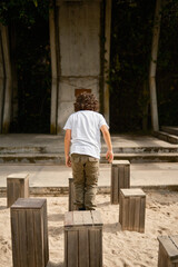 Child jumping and balancing on wooden blocks in a playground