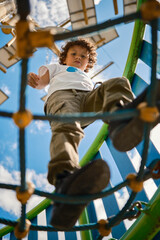 Child walking on a net of ropes on a sunny day