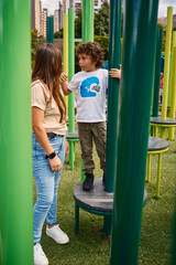 Boy talks to his mother while playing in a playground