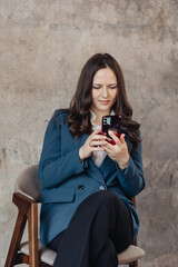 Confident businesswoman using smartphone while sitting in modern office space