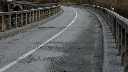Curved empty road with weathered surface and guardrails, autumn travel adventure, rural scenic journey