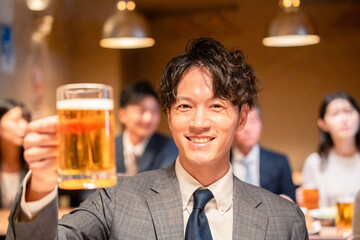 居酒屋でビールの乾杯をするサラリーマンの男性