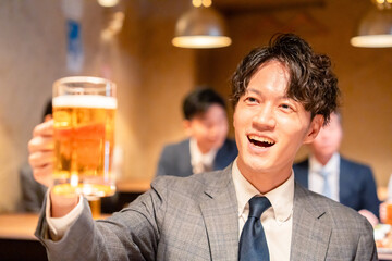 居酒屋でビールの乾杯をするサラリーマンの男性