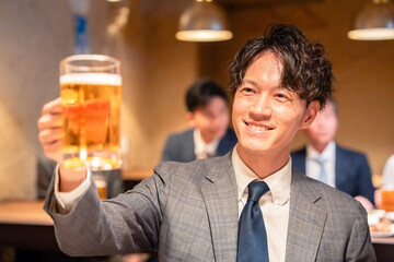 居酒屋でビールの乾杯をするサラリーマンの男性