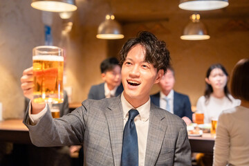 居酒屋でビールの乾杯をするサラリーマンの男性