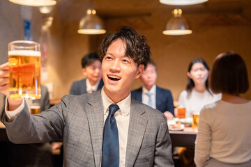 居酒屋でビールの乾杯をするサラリーマンの男性