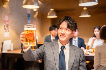 居酒屋でビールの乾杯をするサラリーマンの男性