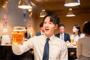 居酒屋でビールの乾杯をするサラリーマンの男性