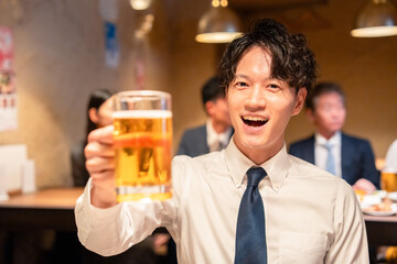居酒屋でビールの乾杯をするサラリーマンの男性