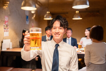 居酒屋でビールの乾杯をするサラリーマンの男性