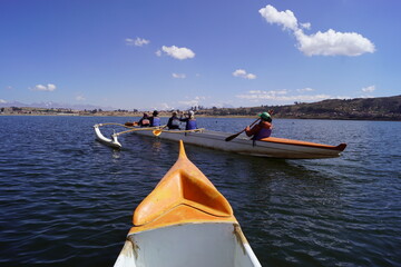 Kayaking in Polynesian kayaks in the Laguna Piuray lake surrounded by the andes mountains near Cusco, Peru