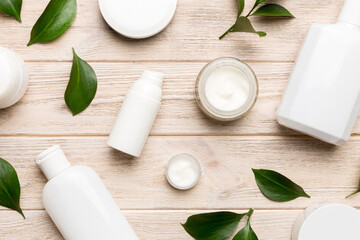 Organic cosmetic products with green leaves on wooden background. Flat lay