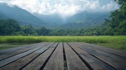 Fototapeta premium Tranquil mountain vista from wooden dock overlooking lush green rice field and misty forest landscape evoking peaceful rural scenery