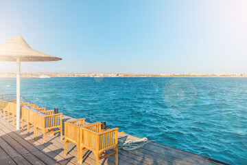 Obraz premium Wooden pier on sea stretching into distance beyond horizon on sunny summer day. Vacation and Travel Concept.