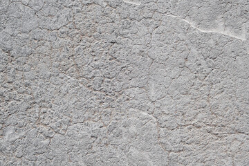 Cracked concrete wall covered with gray cement surface. Grey old wall with shabby damaged plaster or cement and brick background of an vintage dirty exfoliating plaster. Mock up.