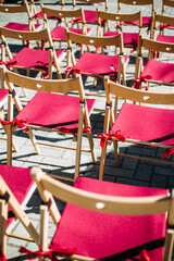 Pattern of red empty chairs for outdoor summer wedding ceremony. Bright pink and wooden seats on grey background