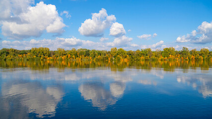 Beautiful blue sky with puffy clouds above the slow river