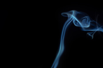 Obraz premium Delicate blue smoke swirls gracefully against a dark background, creating an abstract and ethereal visual effect with fluid motion. Concept of mystery and creativity to overlay on your photos