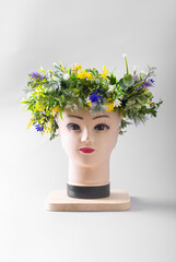 The mannequin's head is decorated with a wreath of flowers.