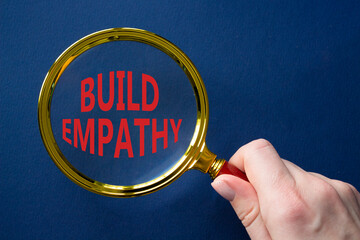 Build empathy symbol. Magnifying glass with words Build empathy. Beautiful deep blue background....