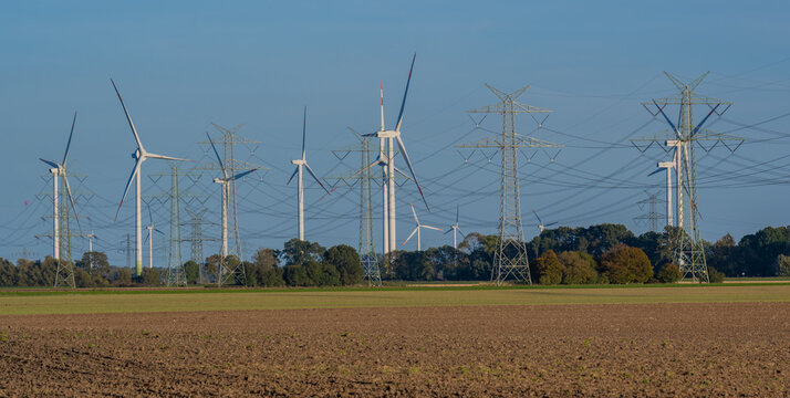 Stromnetz und Strommast Leitungen und im Hintergrund Windkraftanlagen zur Energiegewinnung