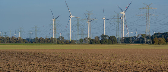 Stromnetz und Strommast Leitungen und im Hintergrund Windkraftanlagen zur Energiegewinnung