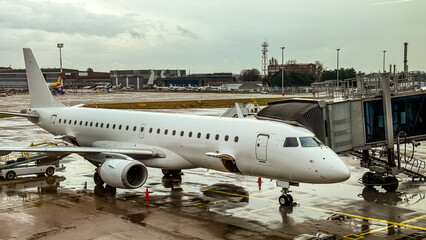 Obraz premium Airport runway with white passenger airplane at boarding gate, travel and transportation concepts, cloudy day