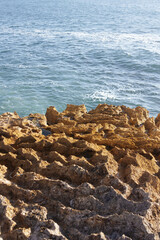 Unusual rock formations by the ocean, showcasing a striking contrast of textures.