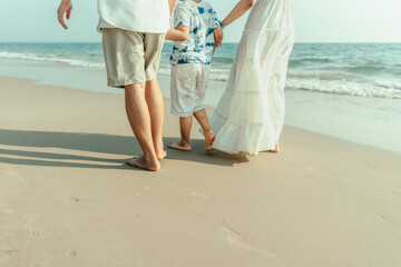 On vacation, travel, or a long weekend, spend time together with family and have fun and happiness by walking hand in hand on a beautiful beach with sunset light.