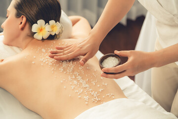Woman customer having exfoliation treatment in luxury spa salon with warmth candle light ambient....