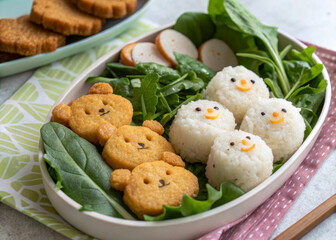 a plate of food with several rice balls decorated with faces, resembling teddy bears. There are also some green leafy vegetables and small bear-shaped snacks around the plate.