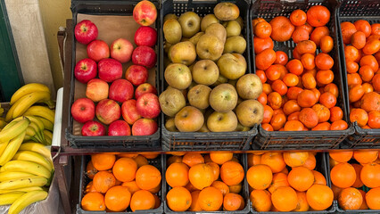 Assorted fresh fruits including apples, pears, and oranges at a vibrant market display, healthy eating, vibrant produce selection, farm to table nutrition concept, colorful freshness in baskets