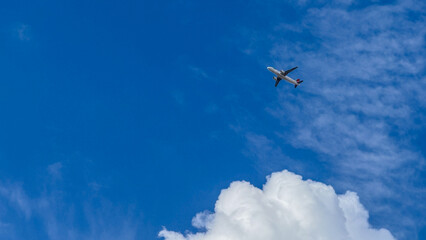 Airplane flying high in clear blue sky with clouds, travel and adventure, aviation freedom