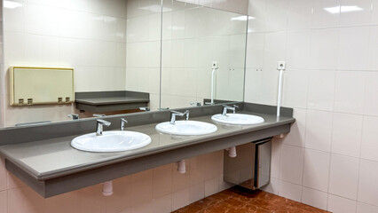 Modern clean public restroom with three sinks and large mirrors, hygiene, commercial interior design